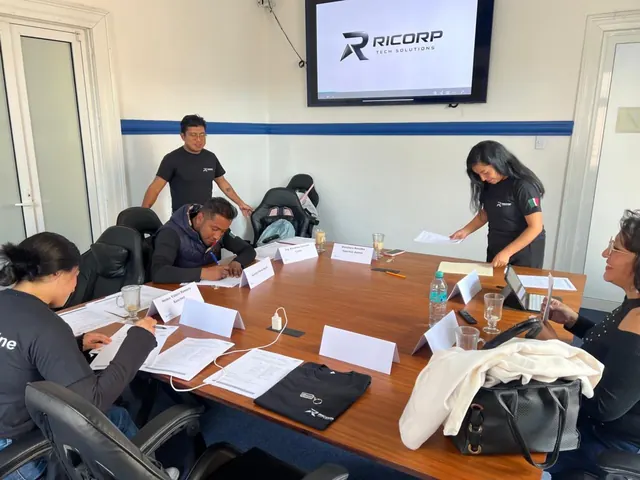Equipo reunido alrededor de una mesa revisando documentos y actividades
