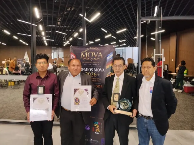 Grupo de participantes mostrando reconocimientos junto a un cartel de evento
